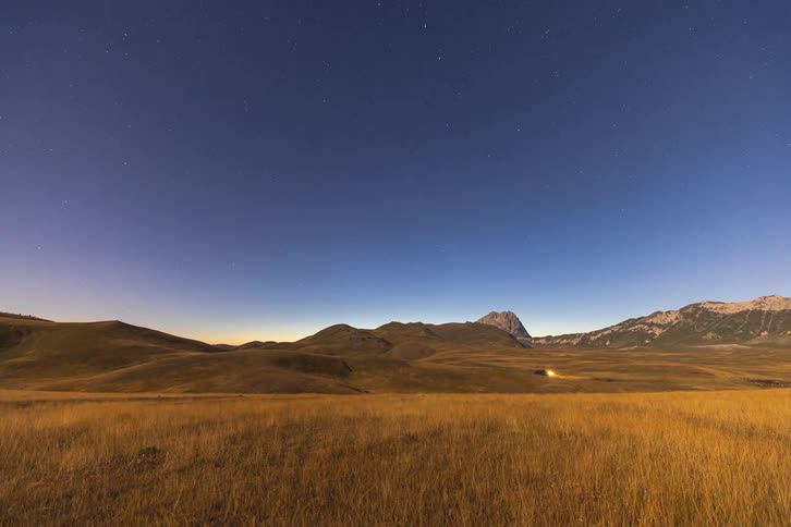 Stunning timelapse captures the transition from a colourful sunset to a brilliant starry night over a vast mountain plain