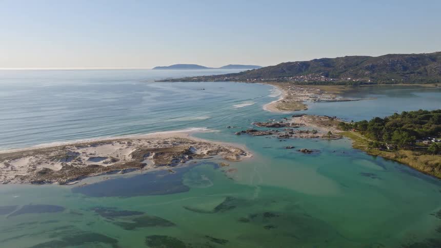A stunning aerial view of a coastal lagoon with turquoise water next to a white sand beach and the ocean on a sunny day