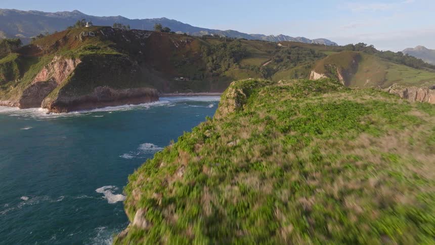 Stunning aerial footage flies over a rugged sea stack to reveal a tranquil beach nestled in a coastal cove
