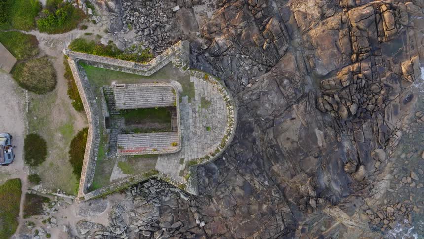 Top-down aerial shot pulls back to reveal the star-shaped Forte da Ínsua nestled on the rocky Spanish coastline
