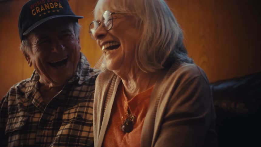 A heartwarming slow-motion close-up of a senior couple sharing a moment of pure joy and laughter together in their home