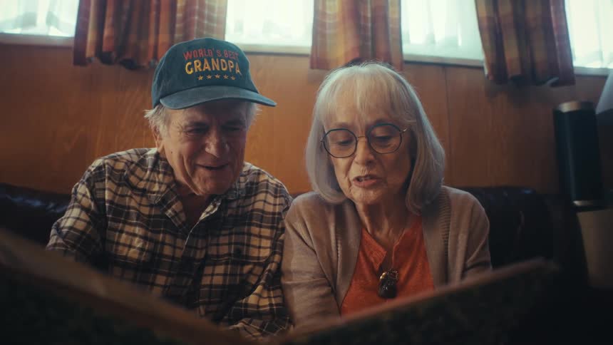 A loving elderly couple looks through a photo album together, smiling and reminiscing about the past
