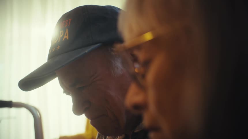 A thoughtful elderly couple has a serious conversation while sitting together in their warmly lit living room at home