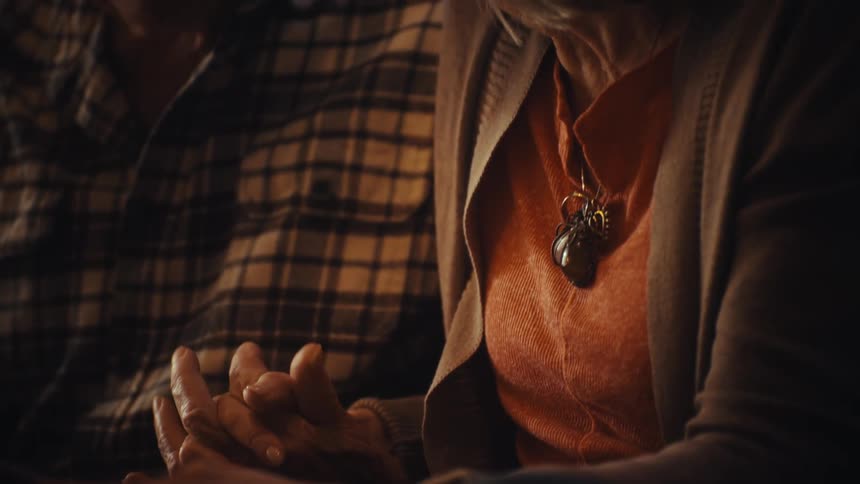 A tender moment as an elderly couple holds hands while reminiscing over a digital photo album in a cozy, warmly lit room