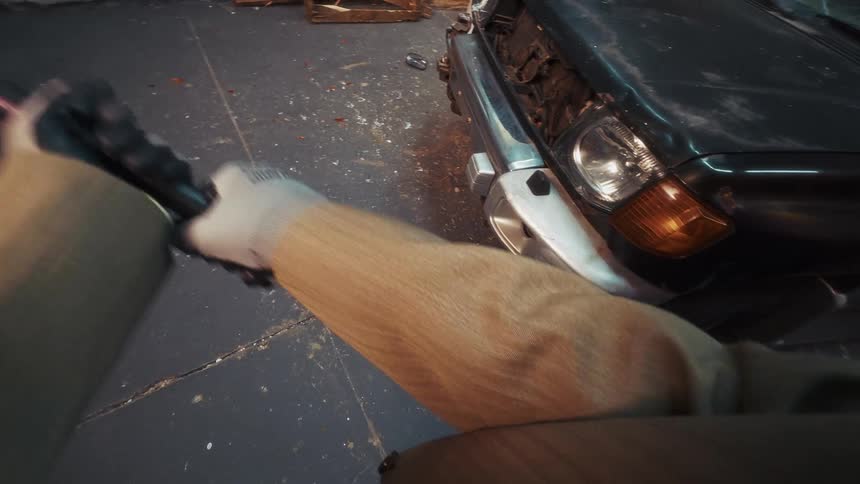 First-person view of someone smashing a car's headlight with a pink baseball bat in slow motion