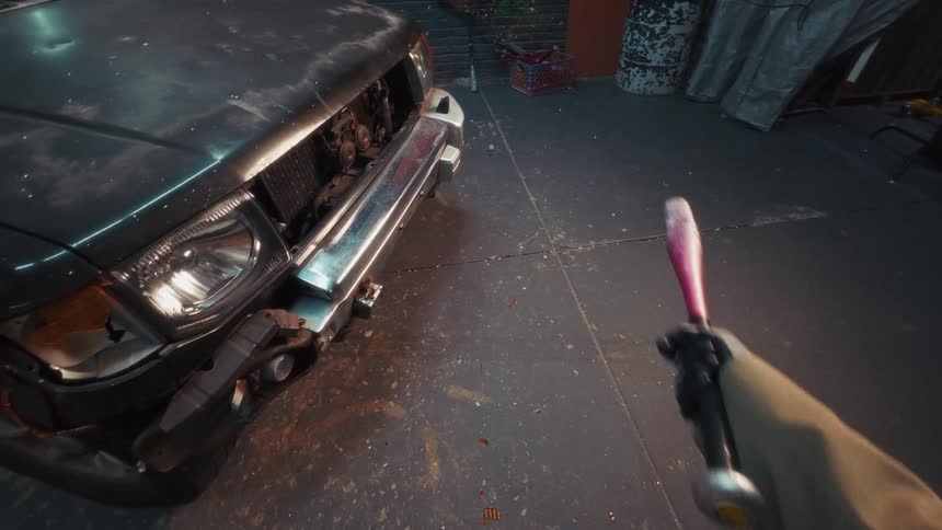 A first-person view shows someone in black gloves picking up a pink baseball bat in a dark, gritty garage next to a damaged car