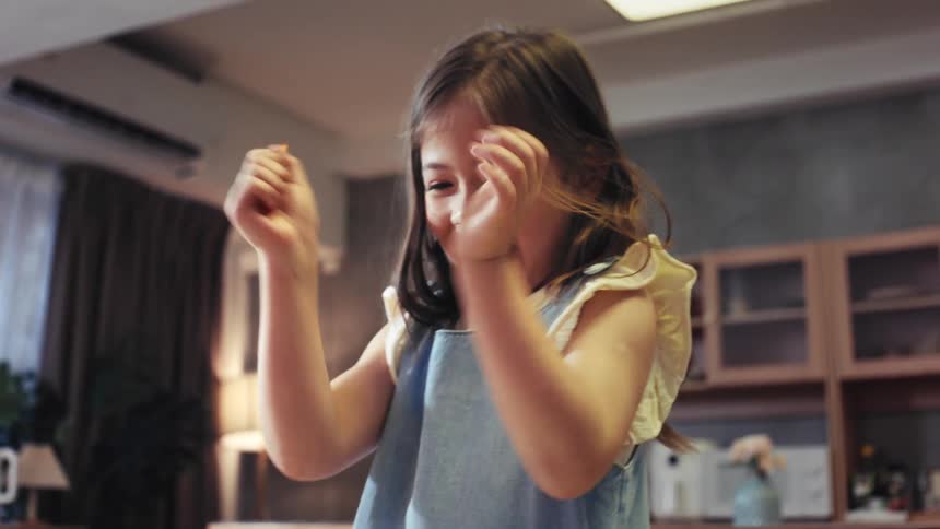 A young girl joyfully claps after finishing a drawing with her mother at home