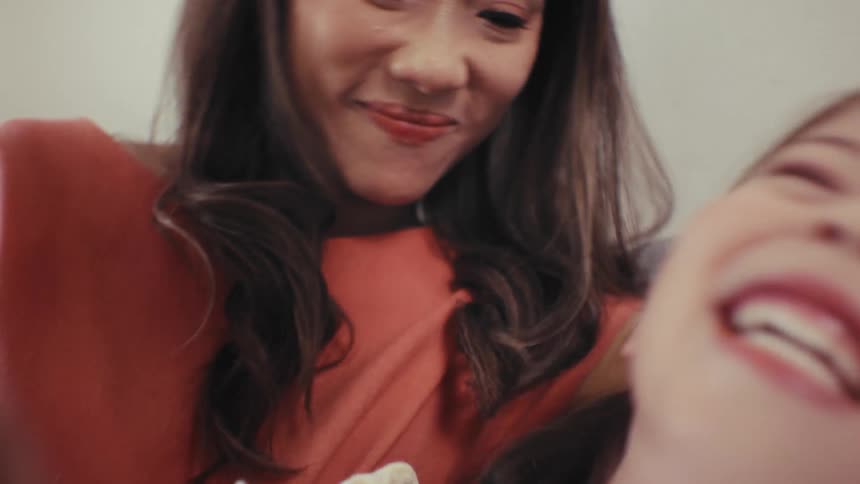 A joyful young girl laughs hysterically in slow motion while her mother playfully teases her in a loving moment at home