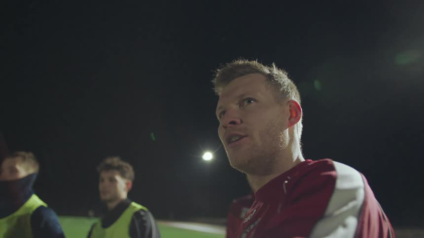 A focused soccer player passionately gives a pep talk to his team under the bright stadium lights at night