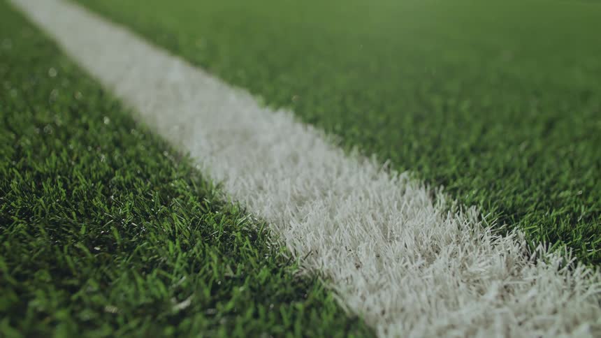 A static close-up shot of a white line on a green artificial turf sports field