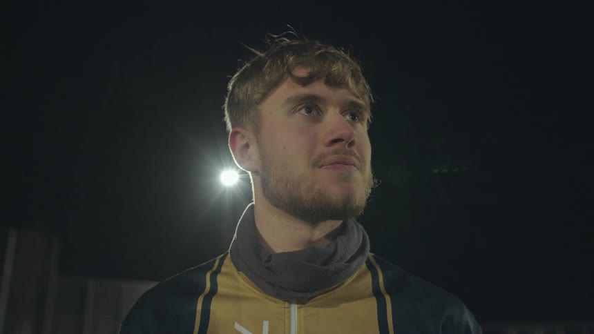Close-up portrait of a thoughtful young male athlete standing under stadium lights at night