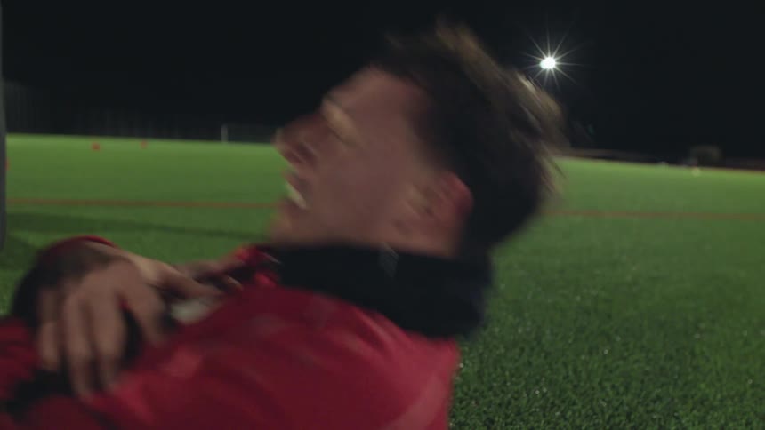 Close-up of an athlete pushing through the pain during a sit-up workout on a soccer field at night