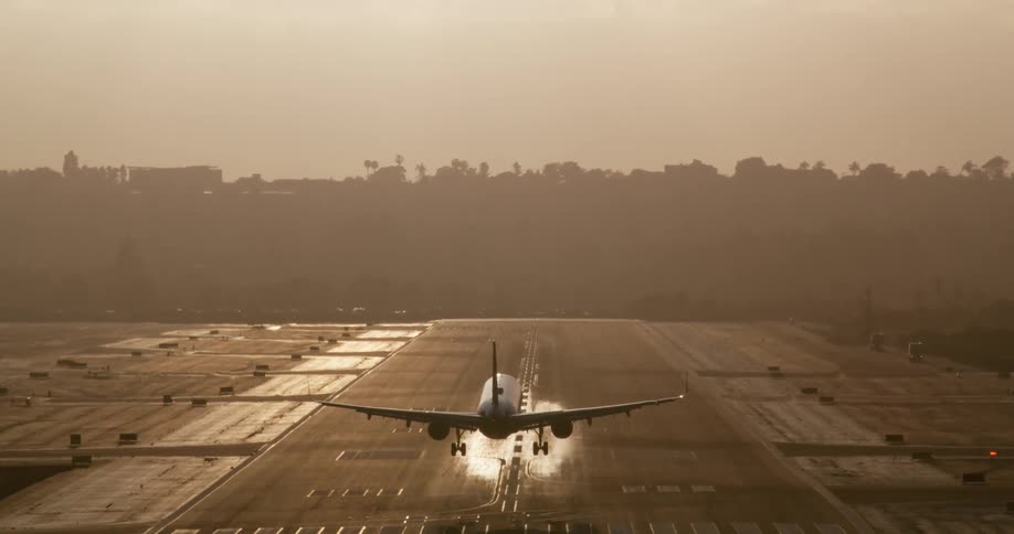 A passenger jet is silhouetted against the sun as it makes a dramatic slow-motion landing on the runway