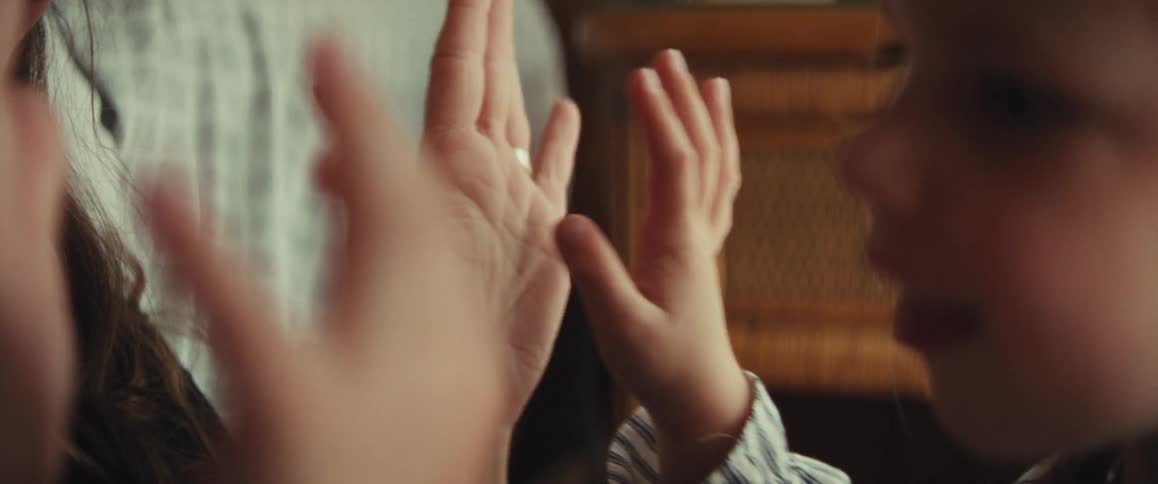 A loving mother and her young daughter share a tender moment, playing a gentle hand game together in a slow-motion close-up
