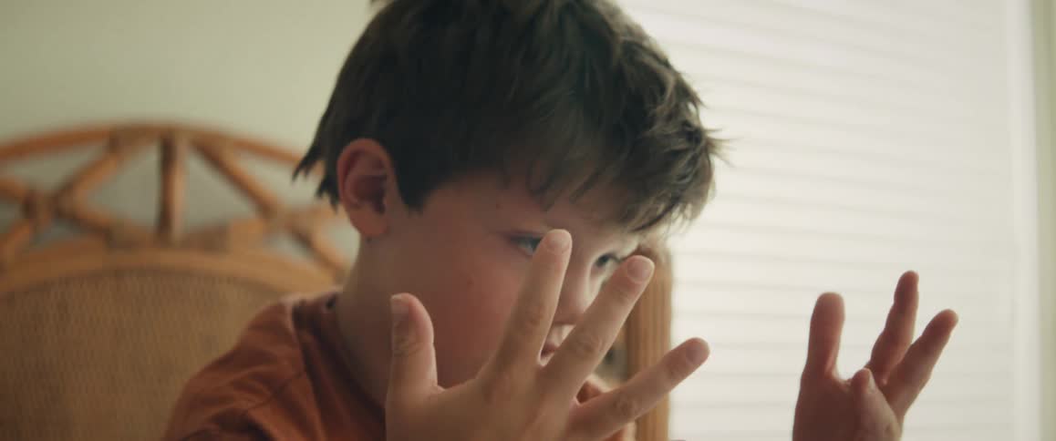 A focused young child slowly counts up to eight on his fingers while learning math
