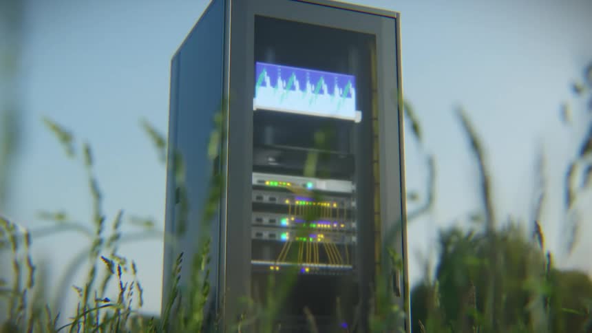A data server rack with blinking lights and a monitor stands in a green field, symbolizing the harmony of technology and nature