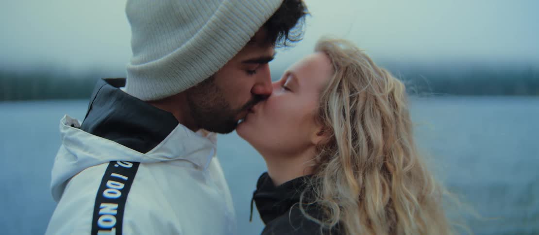 Close up of an intimate couple sharing a passionate kiss by a misty lake in slow motion