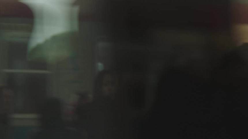 A fast-moving train blurs the view of commuters waiting on the station platform