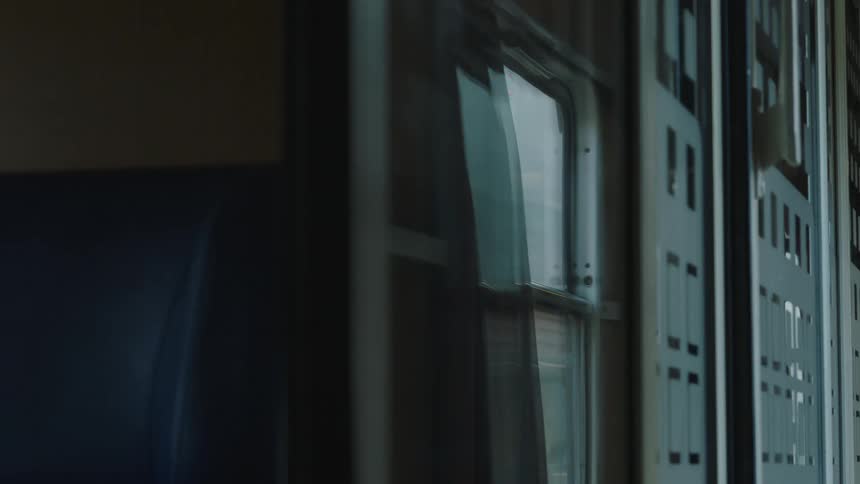 The interior of a moving train car with reflections on the window as the landscape blurs by