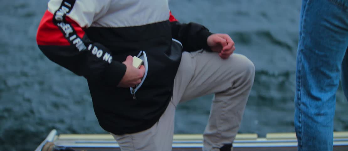 A young man surprises his girlfriend by kneeling down and proposing with an engagement ring on a dock by a lake