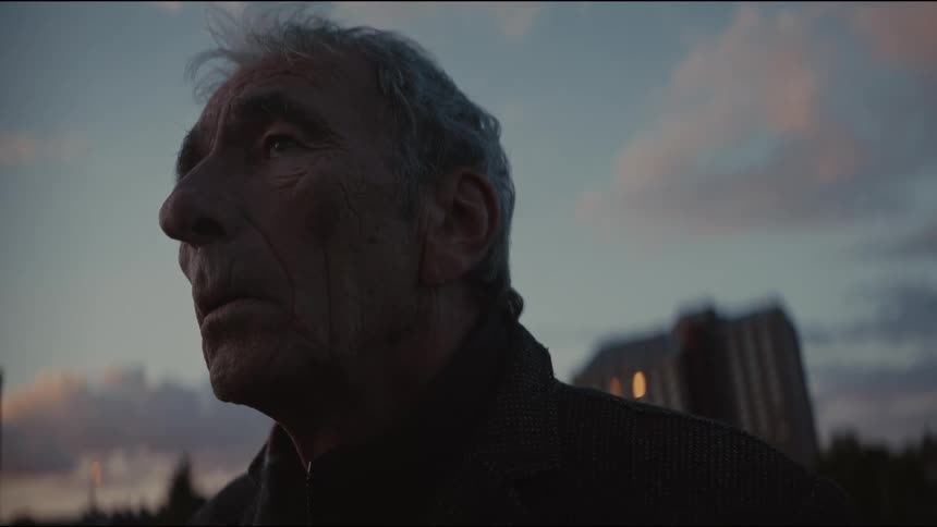 Low-angle close-up of a pensive elderly man smoking a cigarette and contemplating at dusk