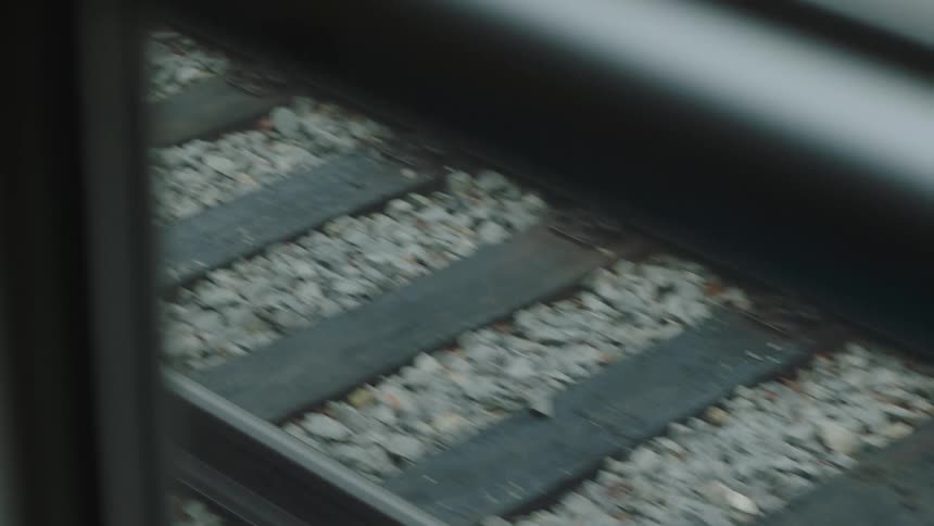 A high-angle close-up shot of railroad tracks moving by as seen from a train window
