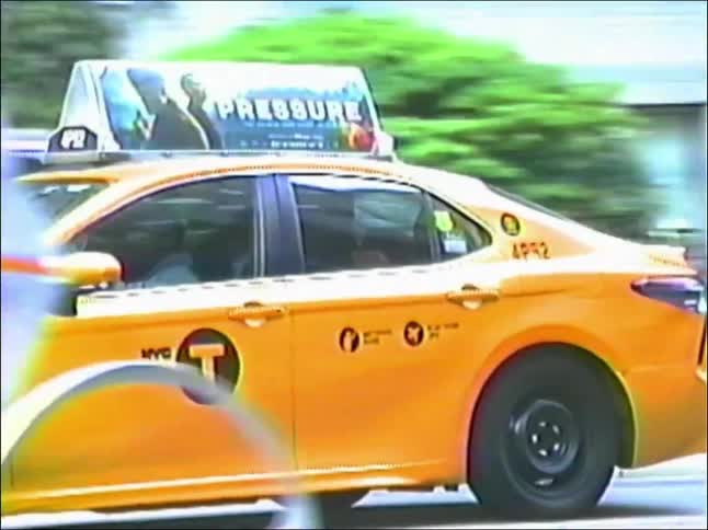 A classic yellow NYC taxi cab drives through a busy city street in this authentic vintage-style footage