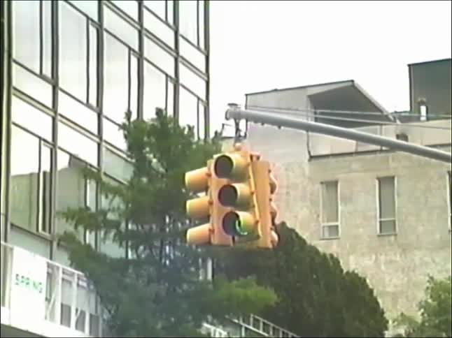 A yellow city traffic light cycles from red to green as a truck passes by