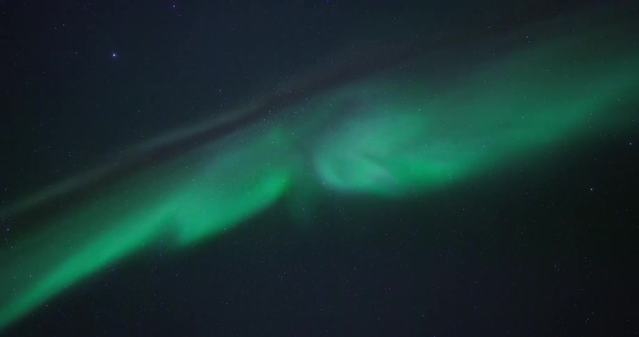 Ethereal green Northern Lights shimmer and move slowly across a clear, star-filled night sky