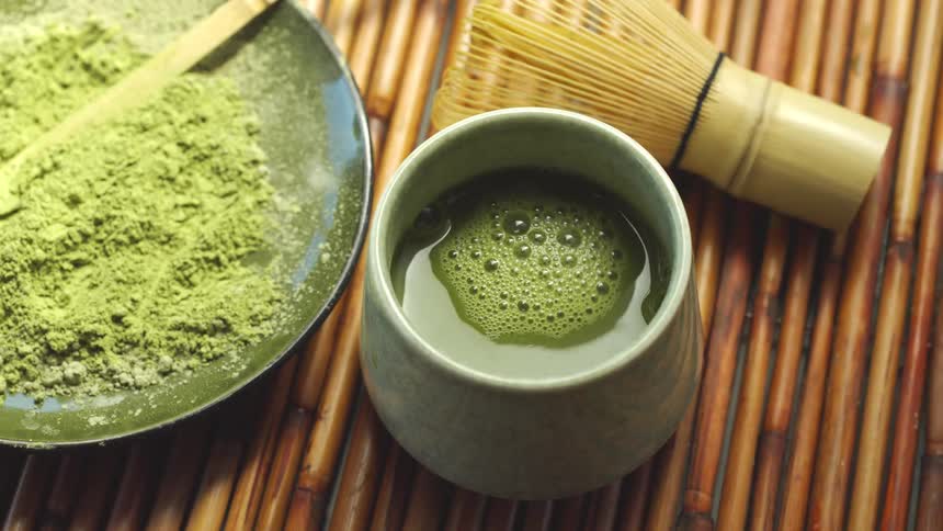 A traditional Japanese tea ceremony in slow motion as frothy matcha green tea is poured into a ceramic bowl