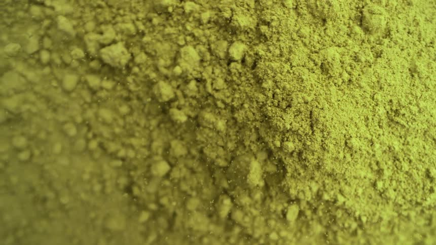 A mysterious cloud of fine, yellow-green powder slowly settles and reveals its granular texture in a macro view