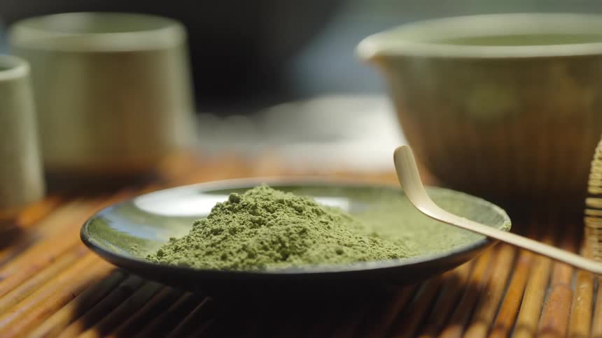 A tranquil close-up pan reveals a traditional Japanese matcha tea ceremony set with powder, a bamboo whisk, and ceramic bowls