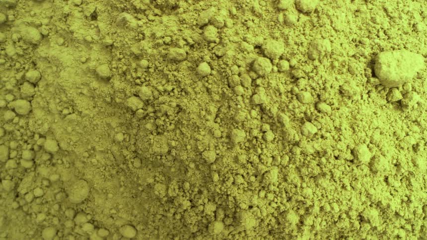 A detailed macro shot slowly pans over a pile of fine, light green matcha tea powder