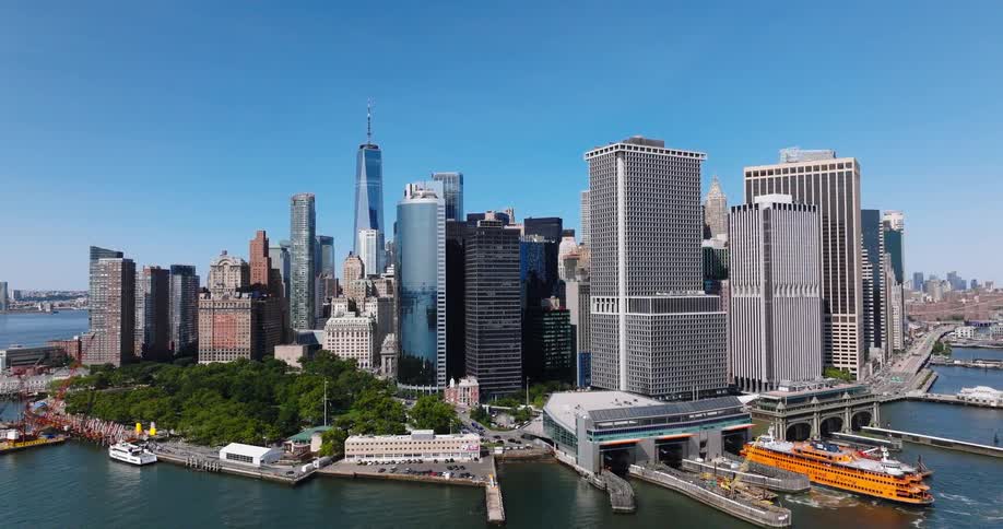 Sweeping aerial pullback shot of the iconic Lower Manhattan skyline and the Staten Island Ferry terminal on a beautiful sunny day