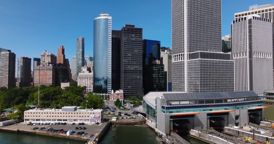 Aerial shot pulls back from the Staten Island Ferry Terminal to reveal the Lower Manhattan skyline on a sunny day