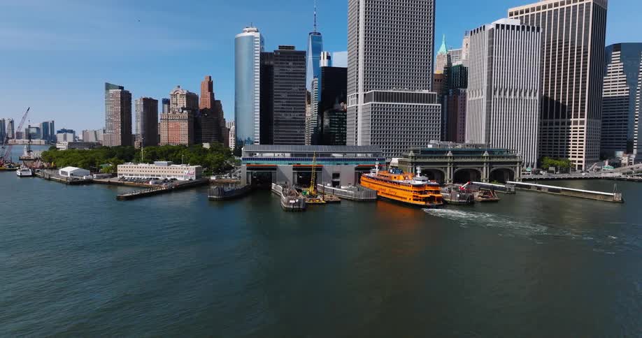 An aerial view shows the iconic orange Staten Island Ferry departing from the Whitehall Terminal in Lower Manhattan on a sunny day