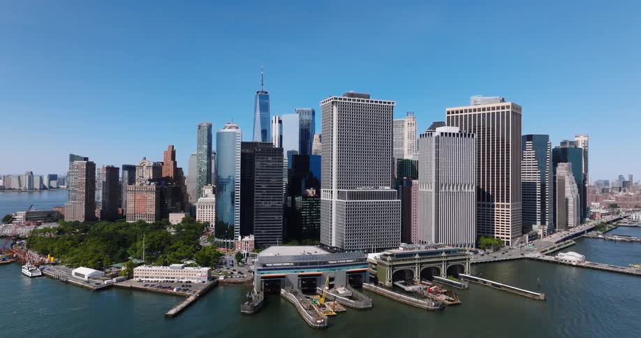 Stunning aerial view slowly reveals the iconic Lower Manhattan skyline and Whitehall Ferry Terminal on a bright, clear day