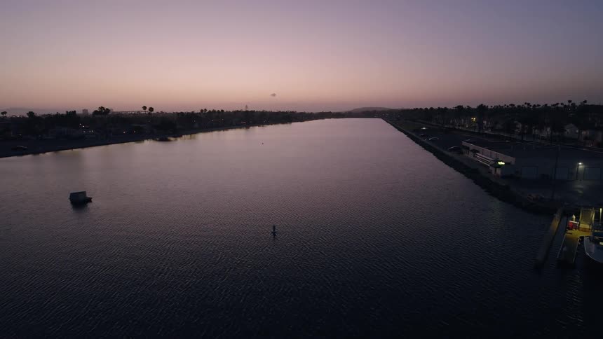 An aerial view of still water in Long Beach, CA as the sky glows at dusk