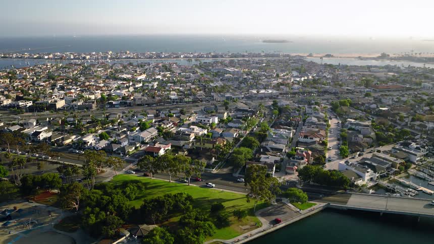 Aerial view ascending over the scenic coastal community of Belmont Shore, Long Beach, showcasing the bay, neighborhoods, and the Pacific Ocean at sunset