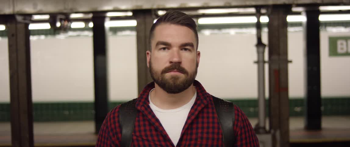 A man stands in front of a moving subway