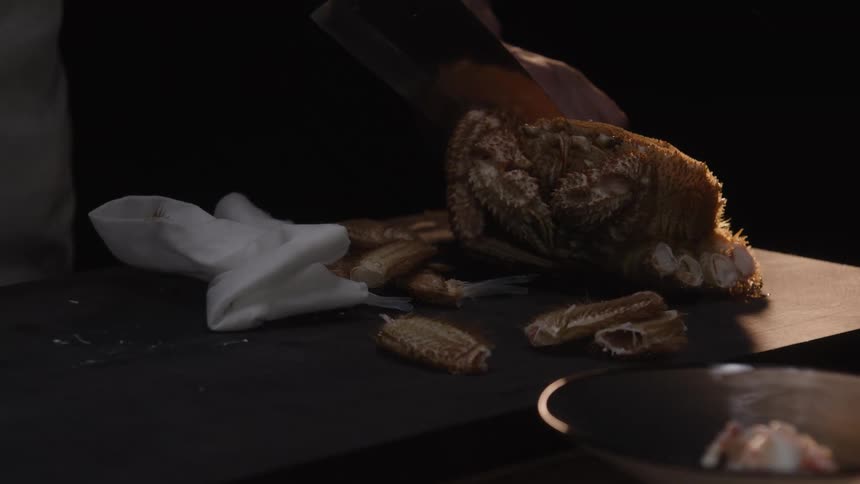 Slow motion footage shows a professional chef carefully cutting a fresh hairy crab with a sharp knife