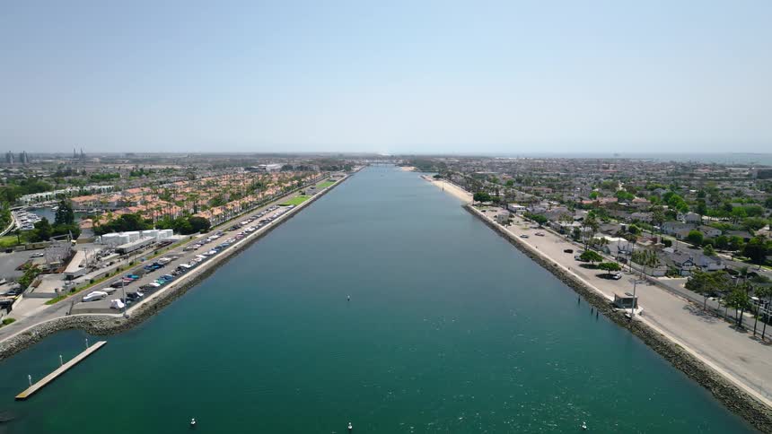 A serene aerial view slowly pushing forward over the calm waters of the Alamitos Bay channel in Long Beach, California on a sunny day