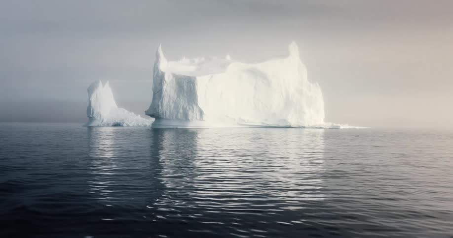 Ethereal shot of a giant iceberg floating in a calm ocean shrouded in fog