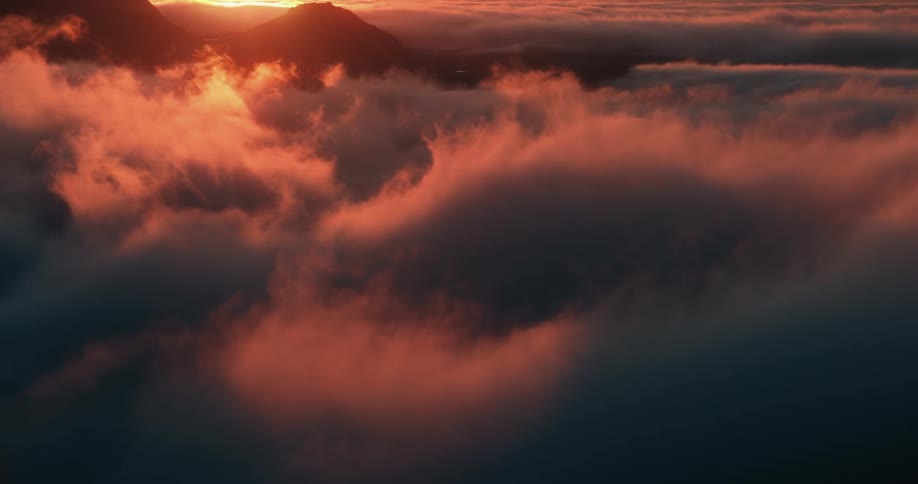 Vibrant orange sunset clouds drift gently over distant mountain peaks in a seamless loop