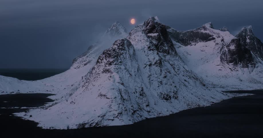 A glowing red moon hangs over a vast and snowy mountain landscape during a cold polar night