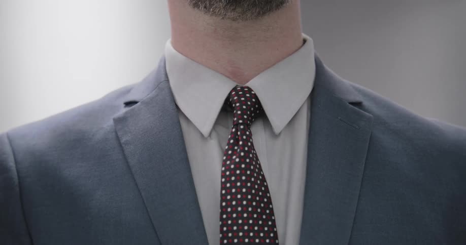 A businessman in a suit jacket adjusts his necktie