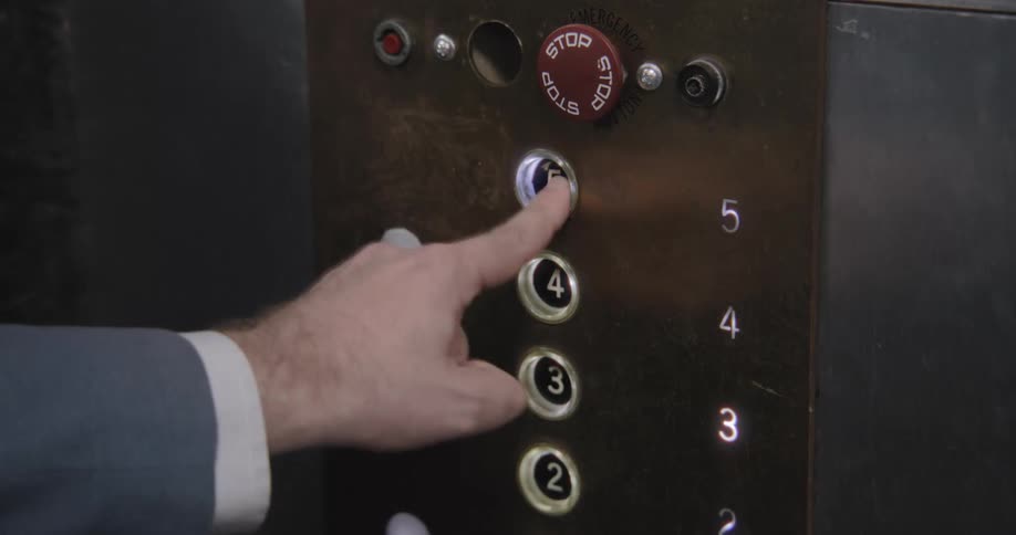 Close up of an impatient man in a suit repeatedly pressing the fifth-floor button on a vintage elevator panel
