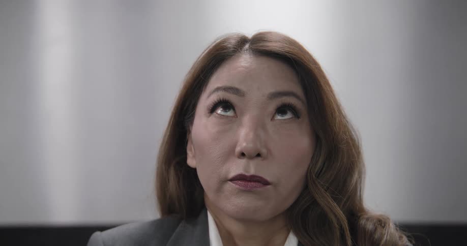 Close up of an annoyed Asian businesswoman rolling her eyes and making funny faces in slow motion