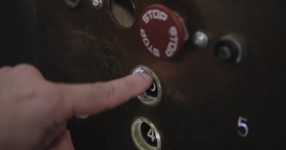 A person's finger repeatedly pushes the fifth-floor button on an old, scratched elevator panel