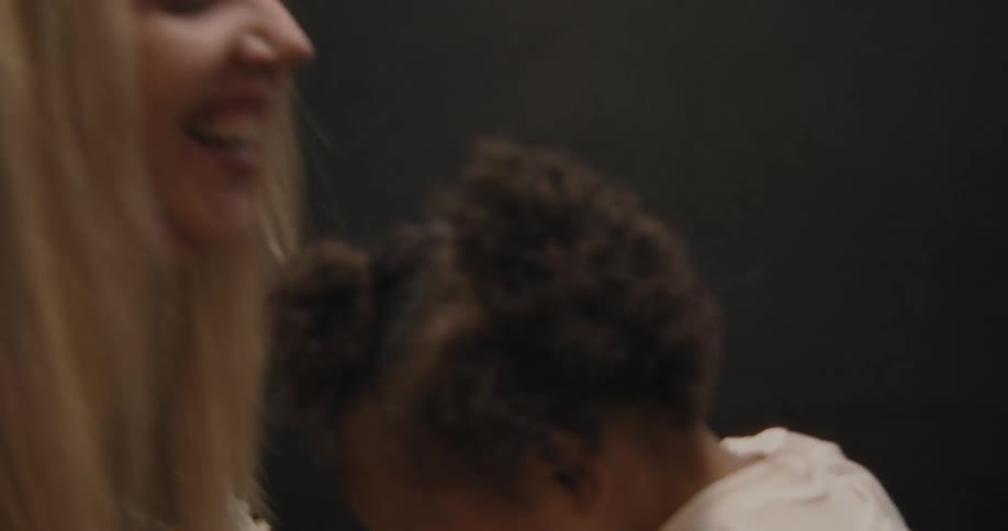 A joyful blonde woman and a cute toddler girl laugh and play patty-cake together before affectionately touching noses in slow motion